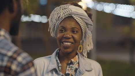 cheerful african american woman chatting with boyfriend outdoors in evening