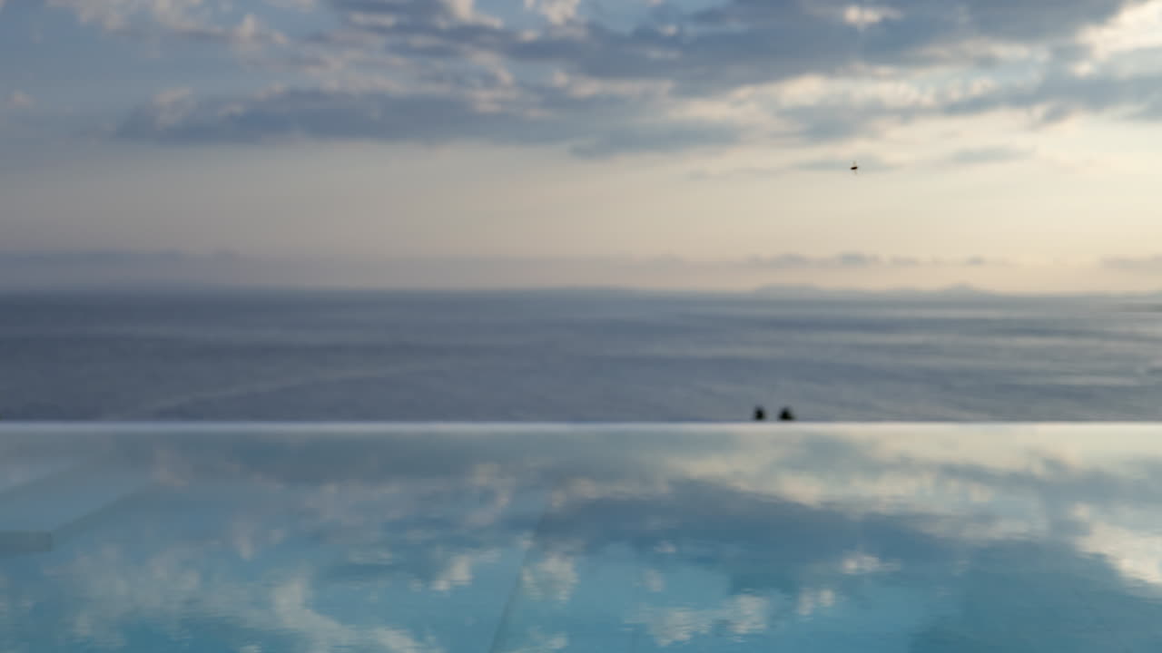 View of an infinity pool and sea and sky with horizon beyond at sunrise