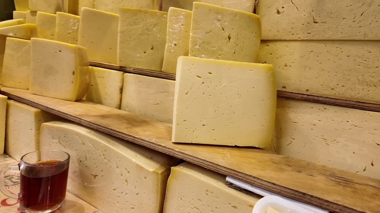 Forme di formaggio giallo su scaffali di legno in un mercato