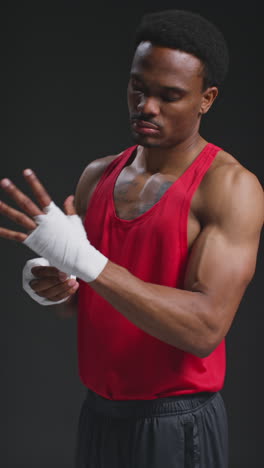 vertical video of male boxer wrapping hands with protective bandages before boxing match or training session 4