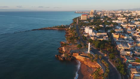 Toma-Aérea-Sobre-La-Avenida-George-Washington,-En-El-Malecón-De-Santo-Domingo-Con-Vista-Al-Obelisco-Femenino-Y-Masculino