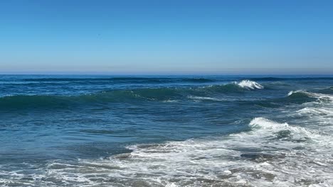 ocean waves crashing and spraying high together during king tide over blue ocean and blue sky