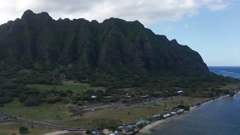 Wide-aerial-panning-shot-of-a-classic-Hawaiian-coastal-volcanic-mountain-ridge-above-Kualoa-Ranch-in-O'ahu