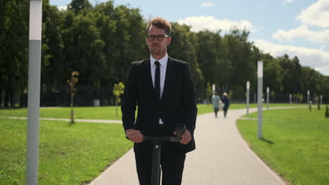 businessman riding an electric scooter in a park