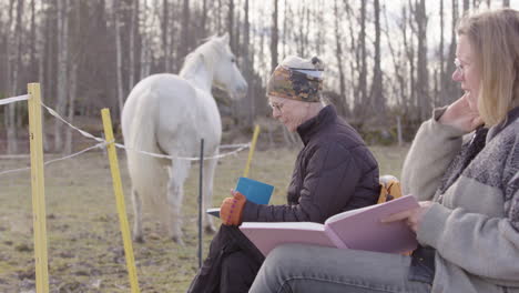 female participants of equine-assisted therapy workshop take notes in journal