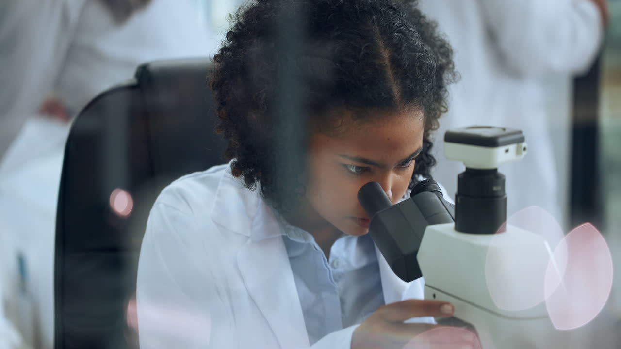Giovane scienziata che guarda attraverso il microscopio in laboratorio