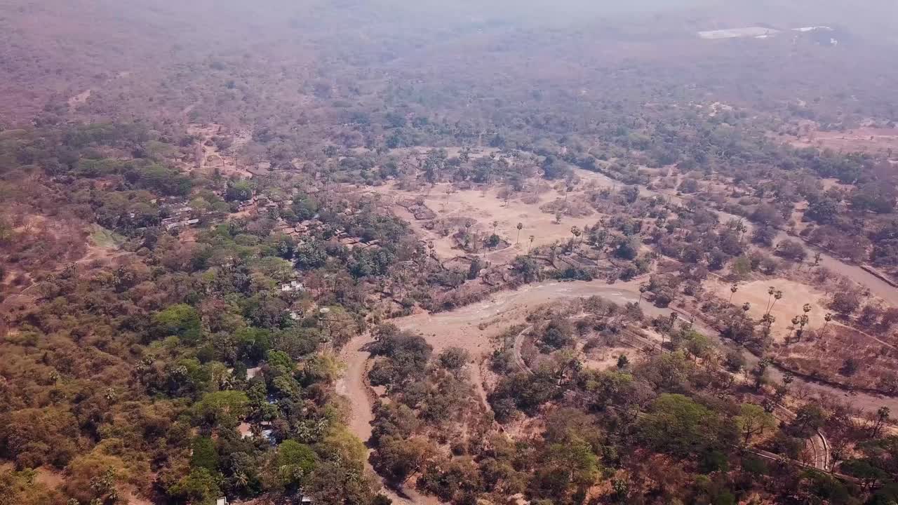 Luftfoto af en flod, der snor sig gennem en tør skov i Sanjay Gandhi Nationalpark, Indien