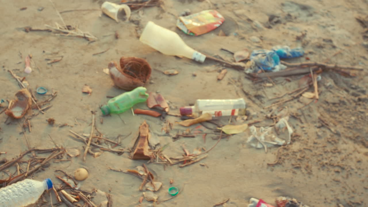 Scatto dettagliato di contenitori di plastica e rifiuti che inquinano una superficie naturale, a simboleggiare la noncuranza ambientale