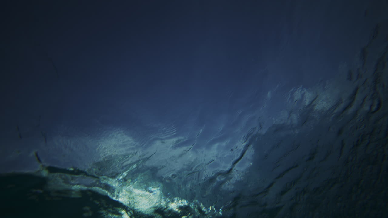 el sol brilla cuando las olas del océano se estrellan la espuma de niebla se extiende en la superficie, bajo el agua mirando hacia arriba