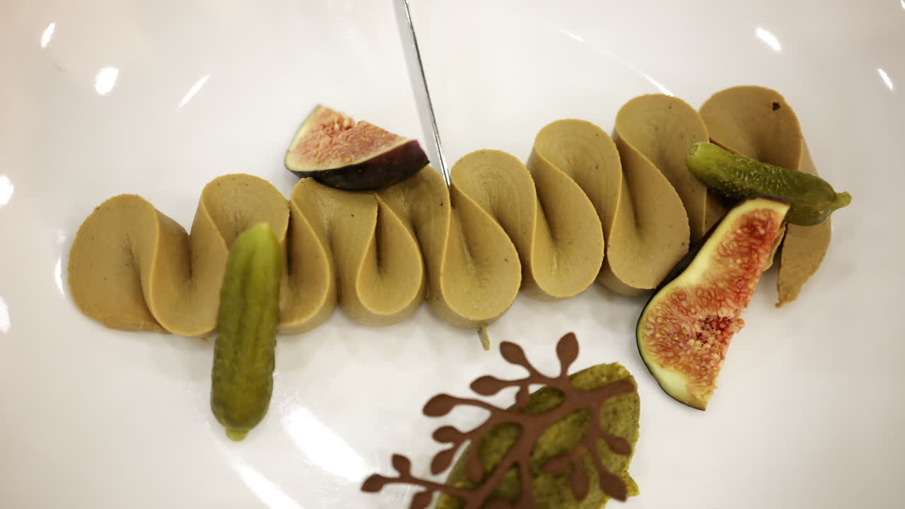 Gourmet plated dish with artistic presentation, featuring figs and decorative elements on a white plate