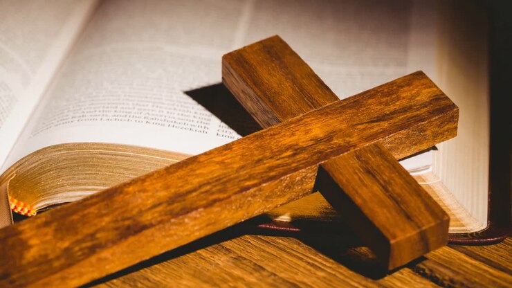 Wooden christian cross on bible over wooden surface