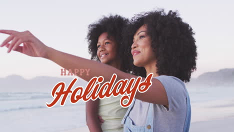 animación de saludos de navidad texto sobre mujer biracial con hija en la playa.