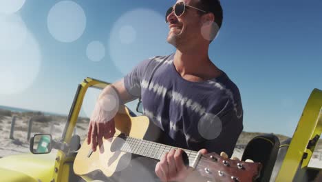 animation of dots over happy caucasian man with guitar on beach