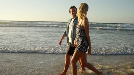 Couple-walking-together-on-shore-at-beach