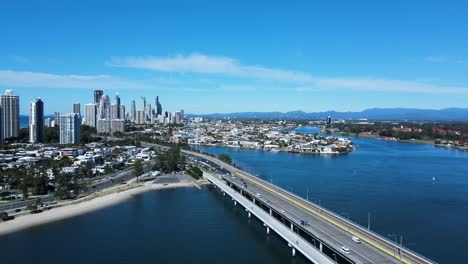 concurrida red de carreteras urbanas y un puente que atraviesa una gran masa de agua que conduce a una expansión metropolitana y a un horizonte imponente.