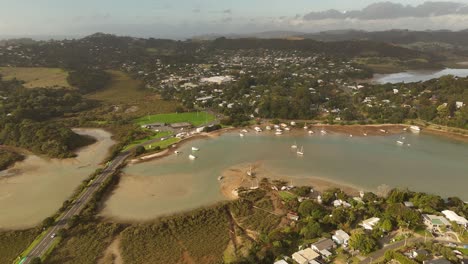 Sunset time in New Zealand with cars on bridge crossing bay. Surfdale Town with houses and Buildings on roof. Aerial wide shot. New Zealand in summer.