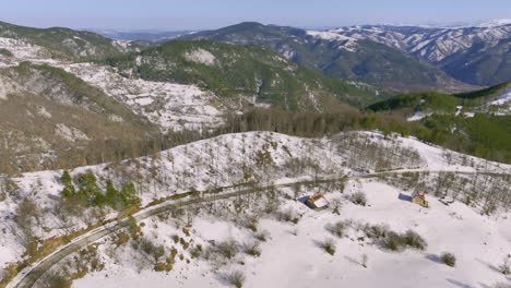 Aerial View of a Snowy Mountain Landscape with Winding Road and Houses