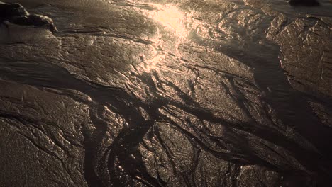 4k-Küstensanderosion-Am-Strand-Nach-Starkem-Regen,-Als-Wasser-Ihren-Weg-In-Den-Ozean-Bahnte