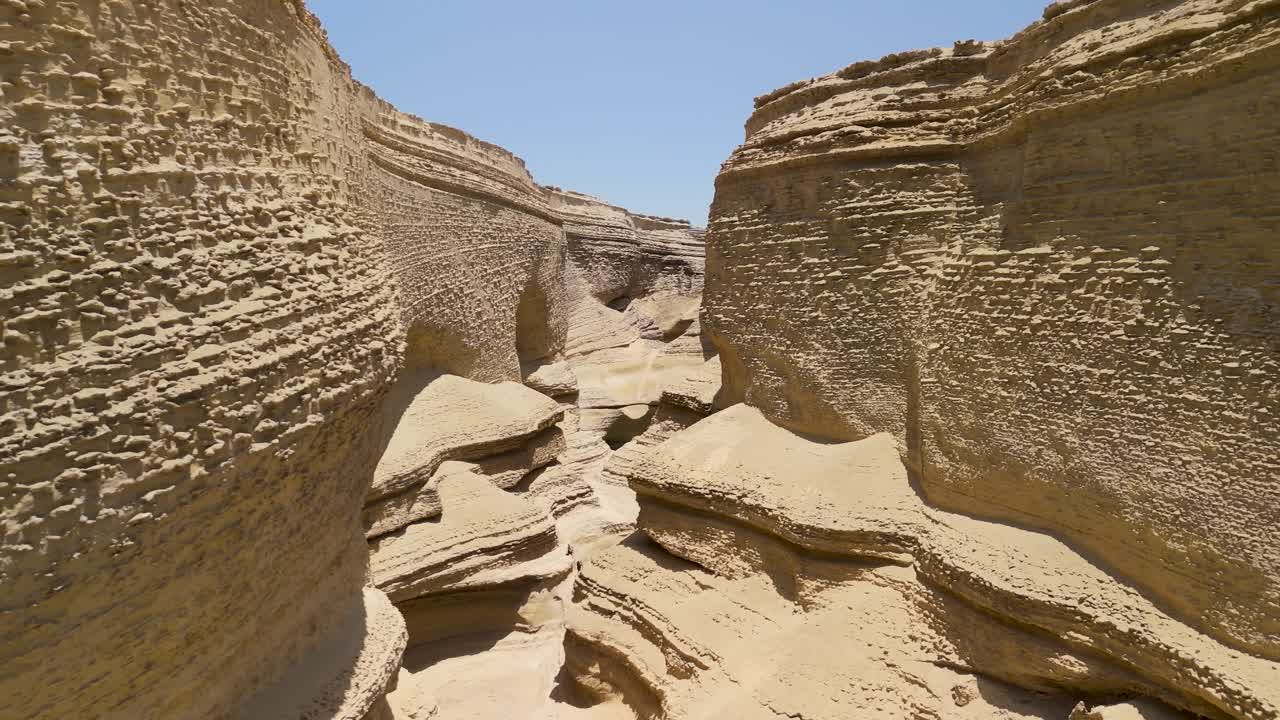 Aerial trucking right shot moving through the narrow and eroded sandstone walls of Cañon de los Perdidos or Canyon of the Lost in the Ica desert Peru