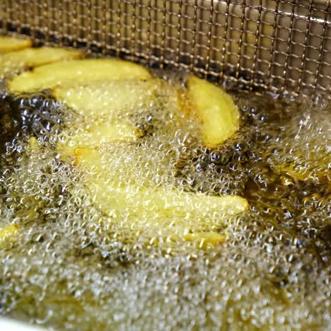 french fries prepared in a big quantity of oil in the deep fryer basket. fast food restaurant concept