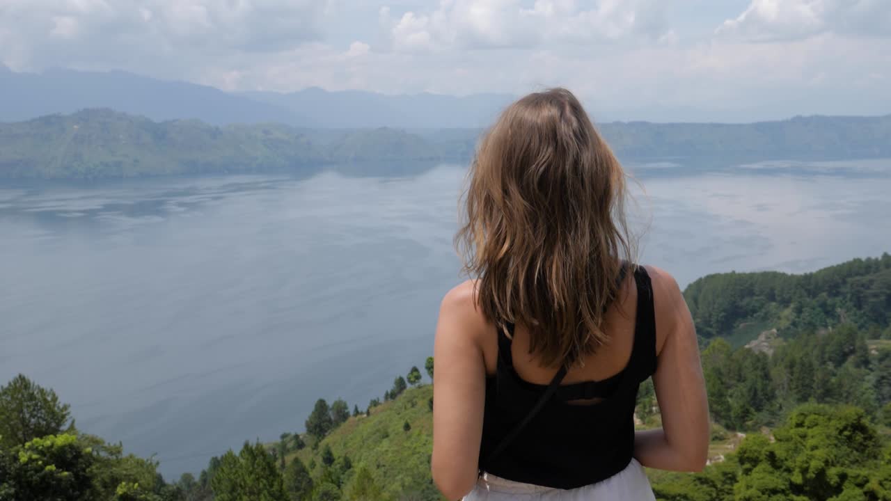 Ultra slow motion shot of young caucasian woman enjoying view of Lake Toba from Samosir Island in North Sumatra, Indonesia