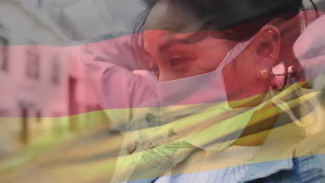 Animation-Der-Flagge-Deutschlands,-Die-über-Einer-Afroamerikanischen-Frau-Mit-Gesichtsmaske-In-Der-Stadtstraße-Winkt