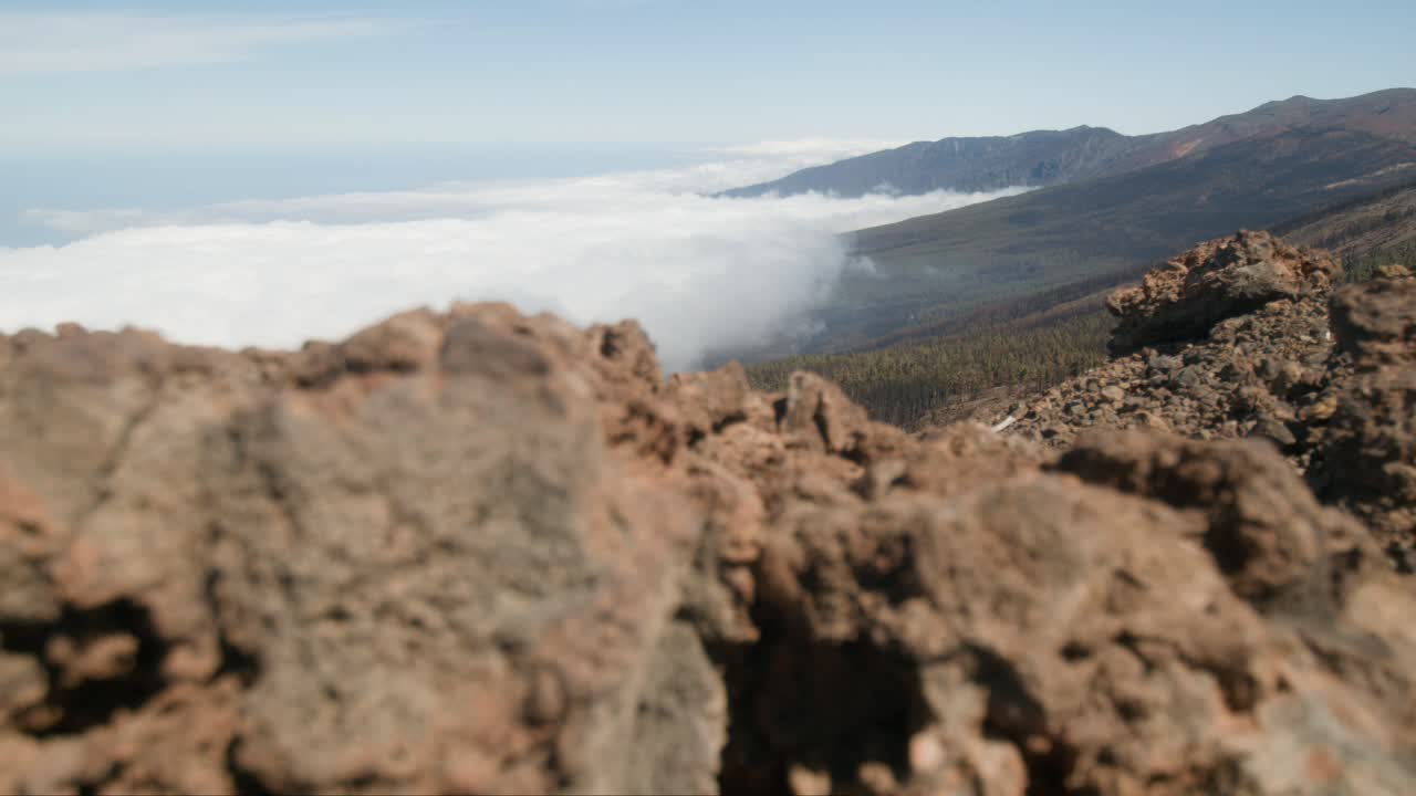 desde detrás de la roca hay una vista de las montañas cubiertas de nubes, parque de tenerife en españa