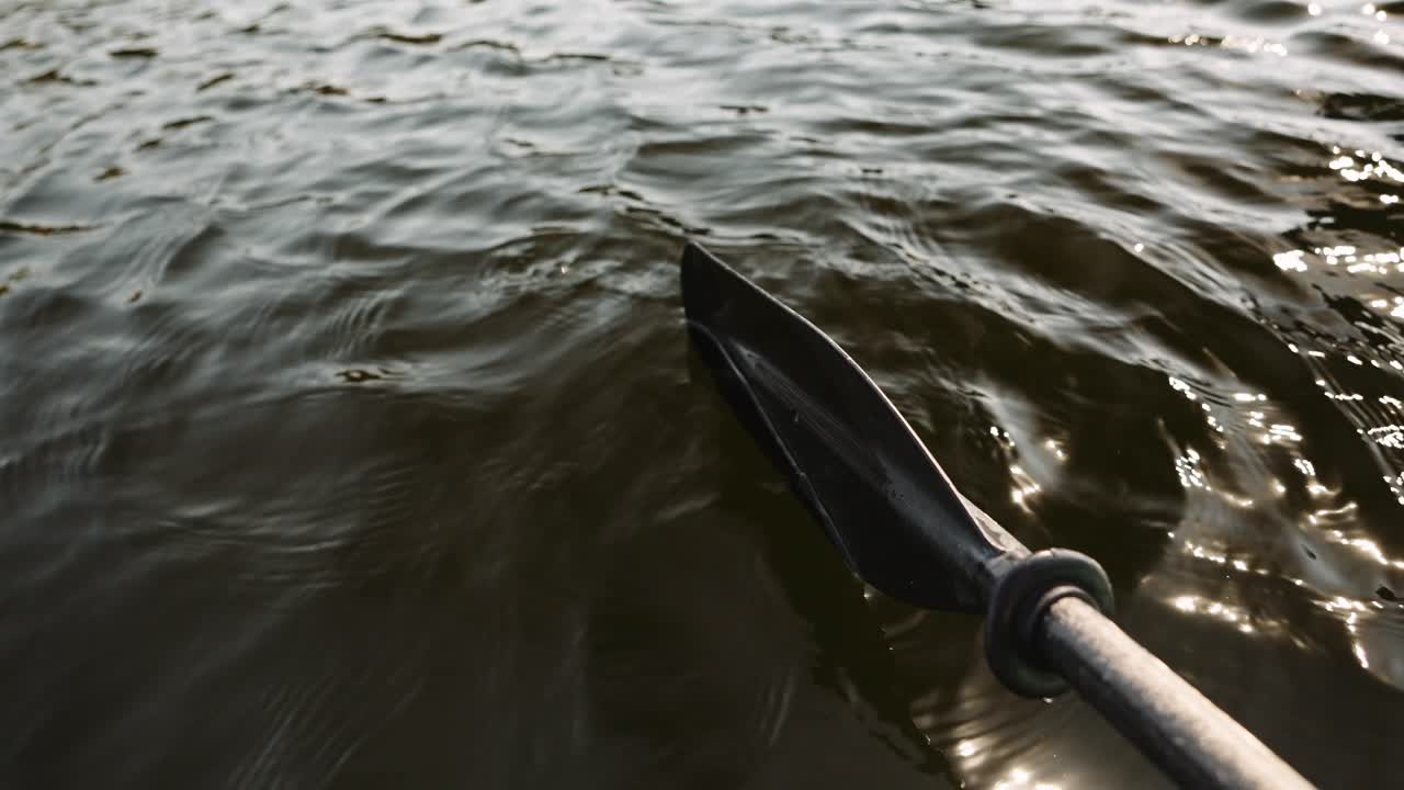 a kayak paddle submerged in the water as the water ripples and light reflections move past it