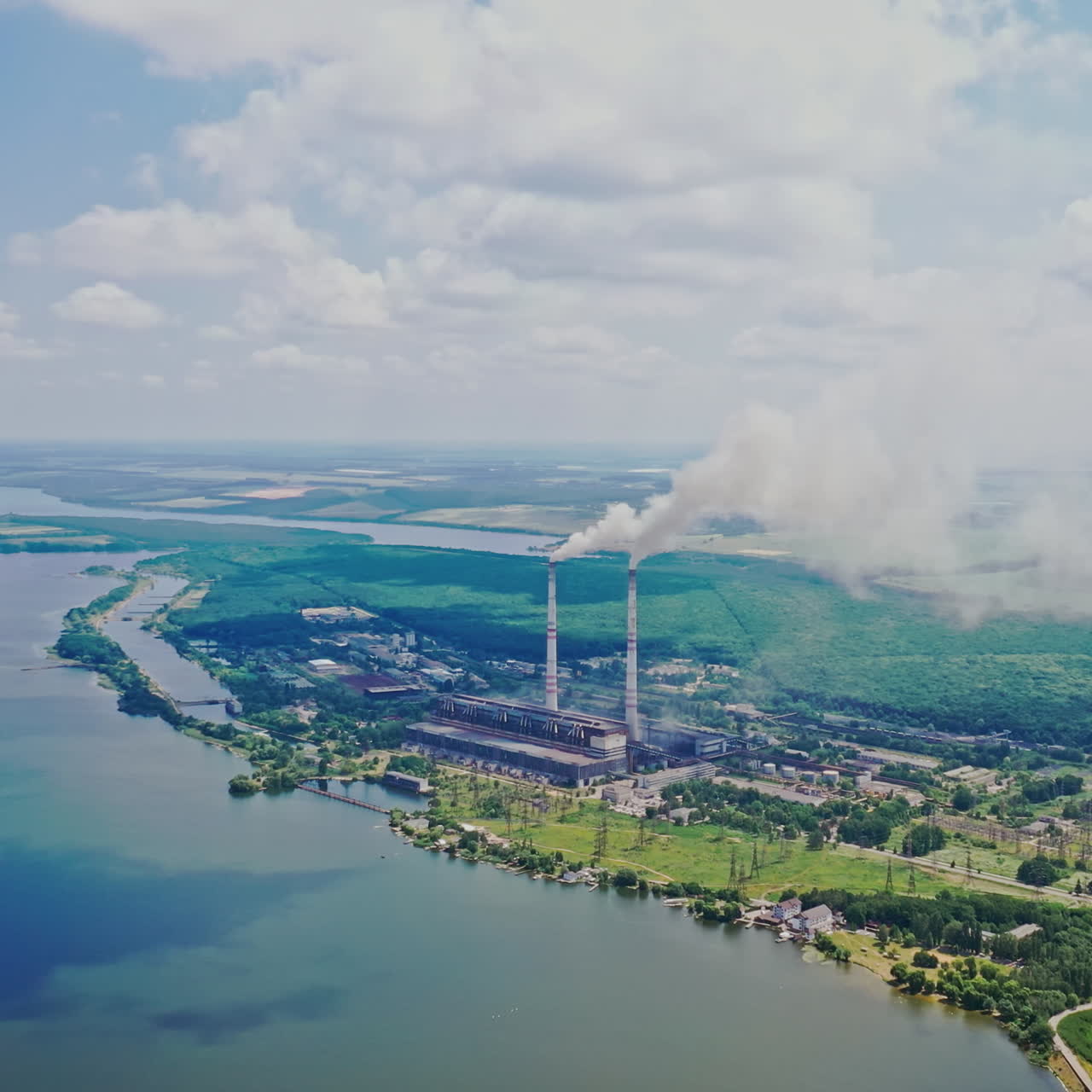 Poor environment in the countryside with huge factory. Harmful emissions from pipes into the environment. Natural scenery and metallurgy plant. Aerial view.