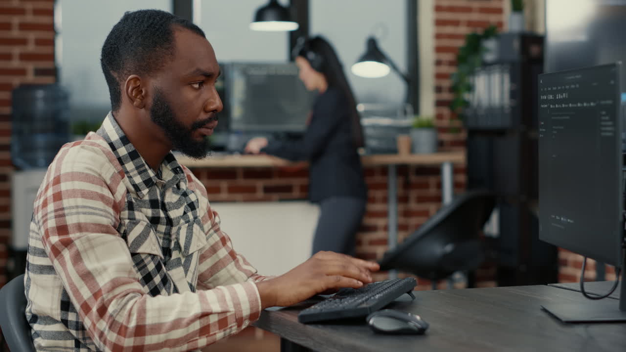 Static portrait of african american system engineer working focused looking at computer screen