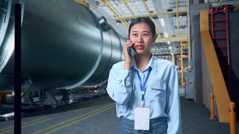 mujer de negocios asiática hablando por teléfono móvil en una fábrica de tubos