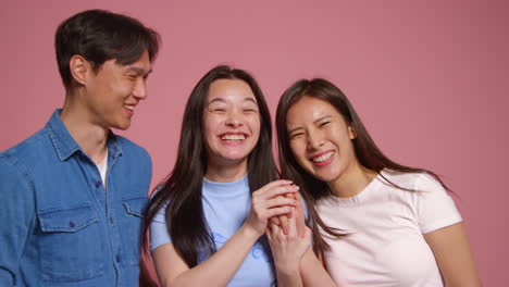 Group-Of-Young-Friends-In-Front-Of-Pink-Studio-Background-Posing-For-Photo-Booth-Style-Portraits