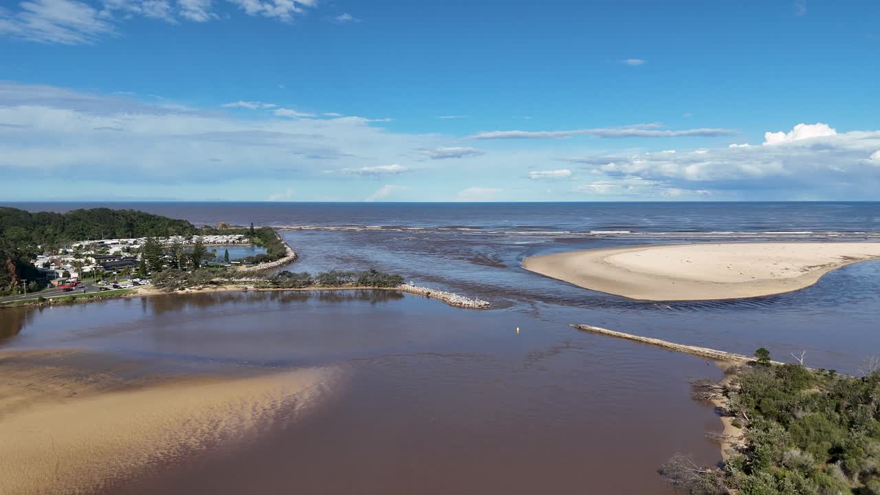 Aerial drone view of Nambucca River mouth, sandbar, estuary, and coastline under clear blue sky