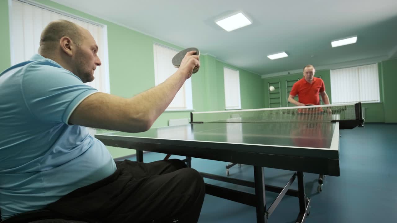 un hombre en silla de ruedas juega ping pong. personas con discapacidad juegan tenis de mesa. rehabilitación de discapacitados. deporte paralímpico.