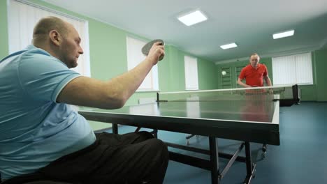 a man in a wheelchair plays ping pong. people with disabilities play table tennis. rehabilitation of the disabled. paralympic sport.