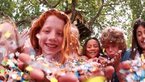 children blowing colorful paper confetti outdoors in a park