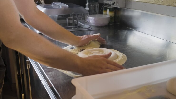 Ripresa con zoom di uno chef che impasta l'impasto della pizza su un bancone da cucina di un ristorante