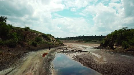 Motorbike-Tour-Through-Dirt-Road-With-Puddles-In-Lake-Magadi,-Kenya