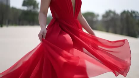 elegantly capturing the graceful movement of a flowing red dress in a breathtaking outdoor setting, showcasing the beauty of fabric and fashion
