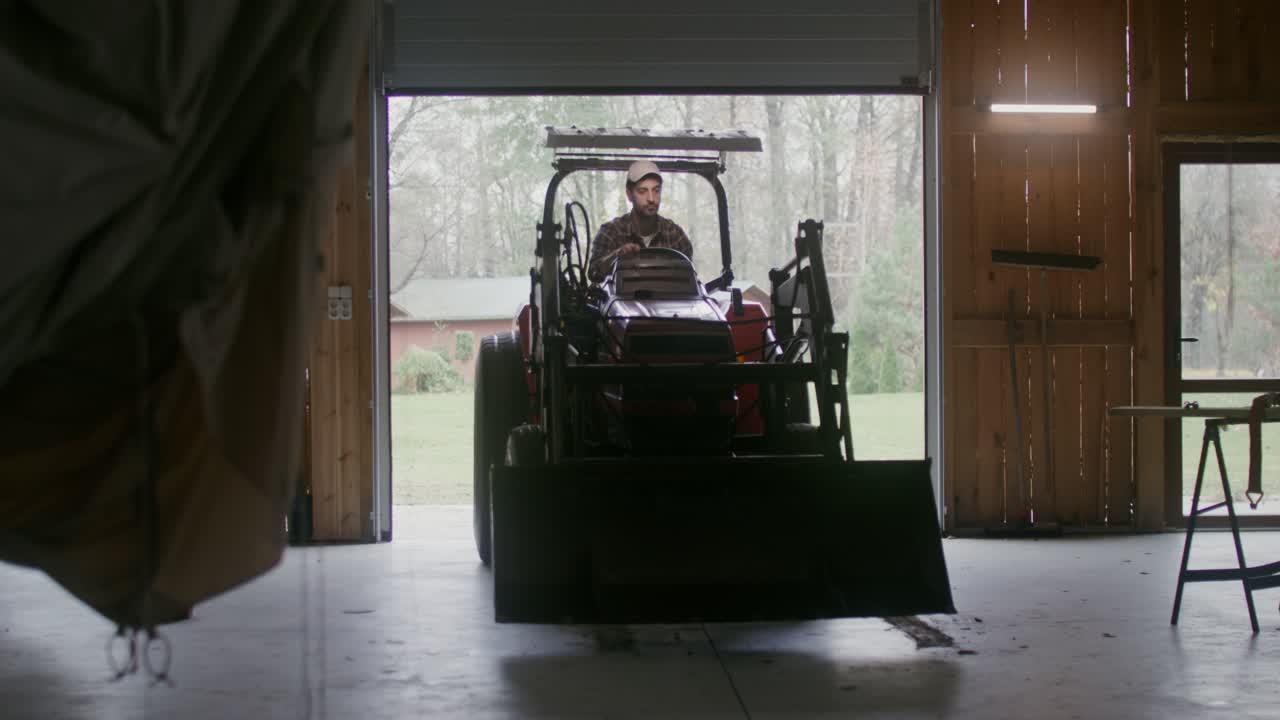 Landmand arbejder på en traktor inde i en lade