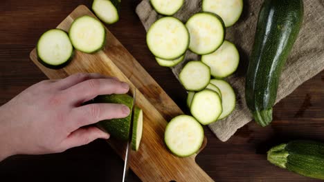 hand men with a knife cut zucchini into slices.