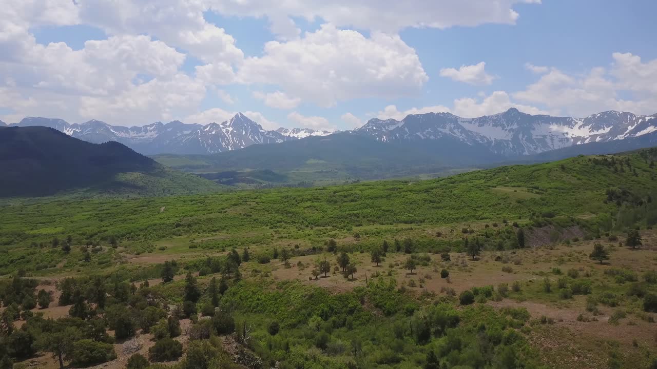Rising, rotating aerial over high green plateau and moutains beyond