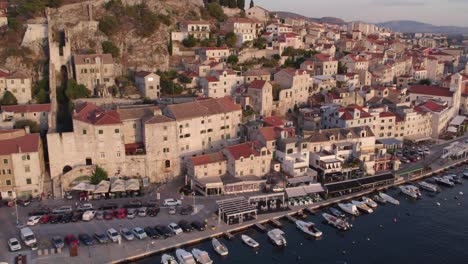 panning shot old town of šibenik croatia with small boats in harbour during sunset, aerial