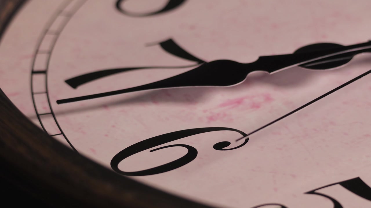 Ripresa macro statica in primissimo piano di un quadrante di orologio antico. La sottile lancetta dei secondi ticchetta costantemente oltre i numeri sei e sette, mostrando il movimento continuo del tempo.