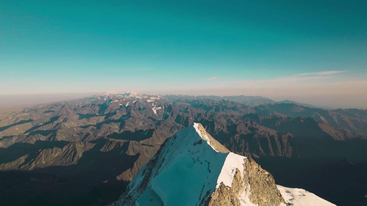 Ripresa cinematografica orbitante con drone di una vetta innevata frastagliata nelle Ande boliviane. Terreno estremamente verticale e ampie vedute montane della Cordillera Real.