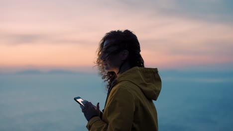 woman using phone at sunrise over clouds