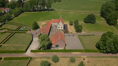 Aerial-tilt-up-shot-of-Castle-Farm-De-Grote-Hegge,-Thorn,-Maasgouw-in-the-province-of-Limburg-surrounded-by-beautiful-nature-and-a-view-of-the-beautiful-dutch-landscape