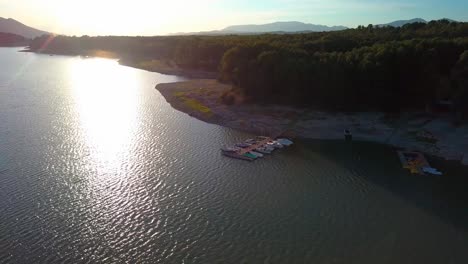 Aerial ascending shot of a woman sitting in a pier with boats moored during the sunset