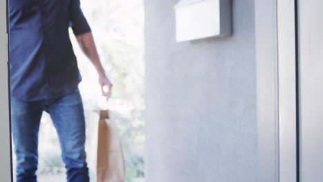cerca del conductor del servicio de entrega a domicilio entregando bolsas de comida para llevar al cliente femenino en la puerta principal