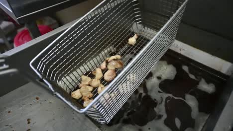aceite burbujeante en freidora cocinando pequeños trozos de carne